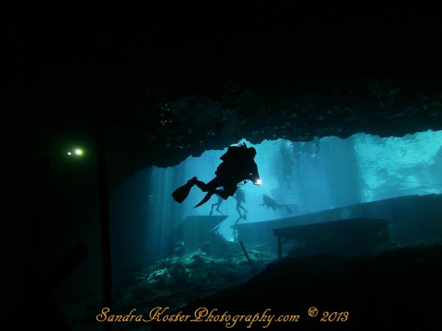 Blue Grotto Dive Resort - Divers with lights entering the cavern zone