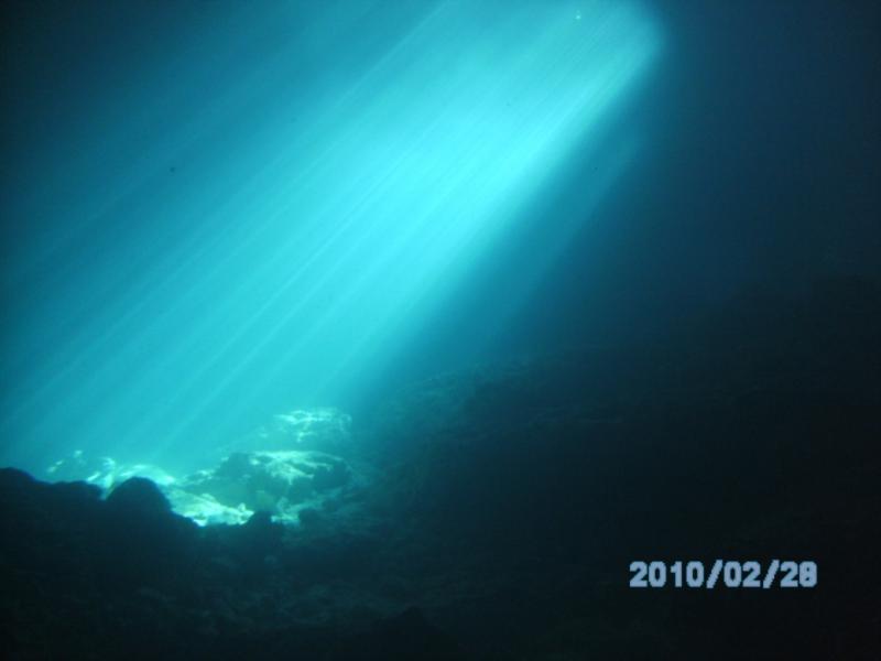 Shafts of light underwater from the hole in the roof of the grotto