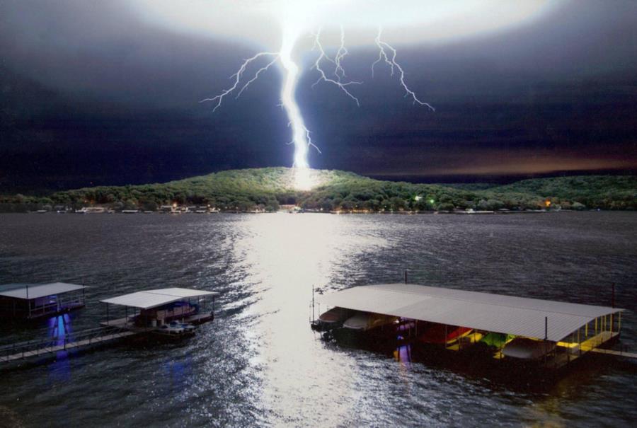 Lightning on hill overlooking lake and marina